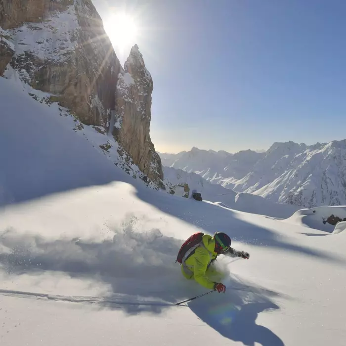 Skifahrer im Neuschnee abseits der Piste in den Bergen im Winter bei Sonnenschein