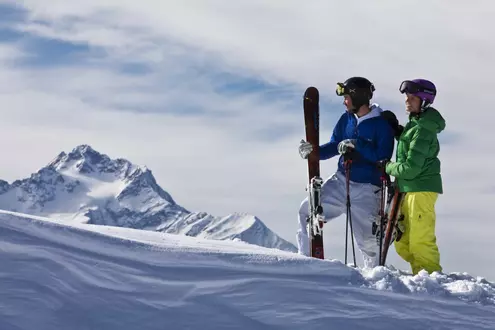 Pärchen genießt beim Skifahren die Aussicht und das verschneite Bergpanorama