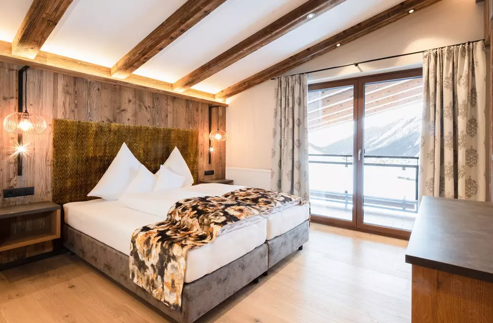 Doppelbett in einem modern eingerichteten Hotelzimmer mit rustikaler Optik