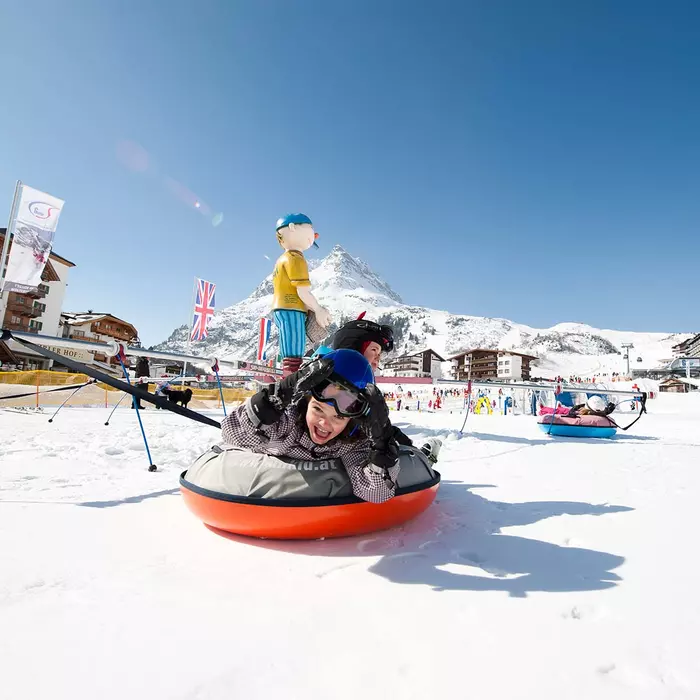 Kinder mit Skiausrüstung und Helm in einem Karusell im Schnee auf Luftpolstern
