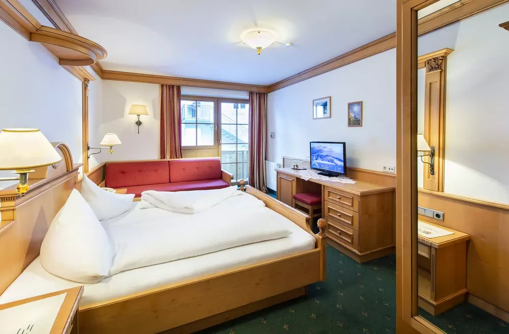 Hotelzimmer mit Doppelbett, Liegesofa, Schreibtisch und eigenem Balkon