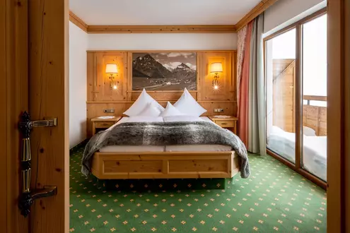 Doppelbett in einem Hotelzimmer mit Vertäfelung und verschneitem Balkon