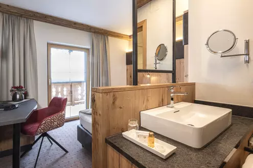 Kleines, modernes Hotelzimmer mit freistehendem Bad, Balkon und Schreibtisch mit Fernseher