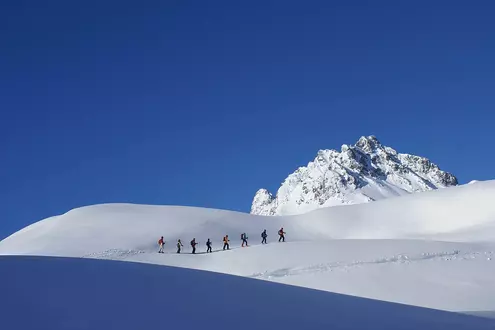 Skifahrer beim Skitourengehen in den Bergen bei blauem Himmel und Sonnenschein