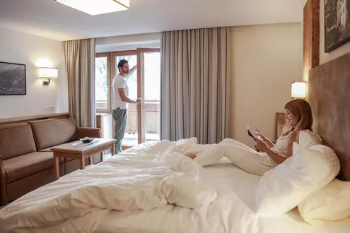 Paar im Hotelzimmer mit Doppelbett, Sofa und Balkon
