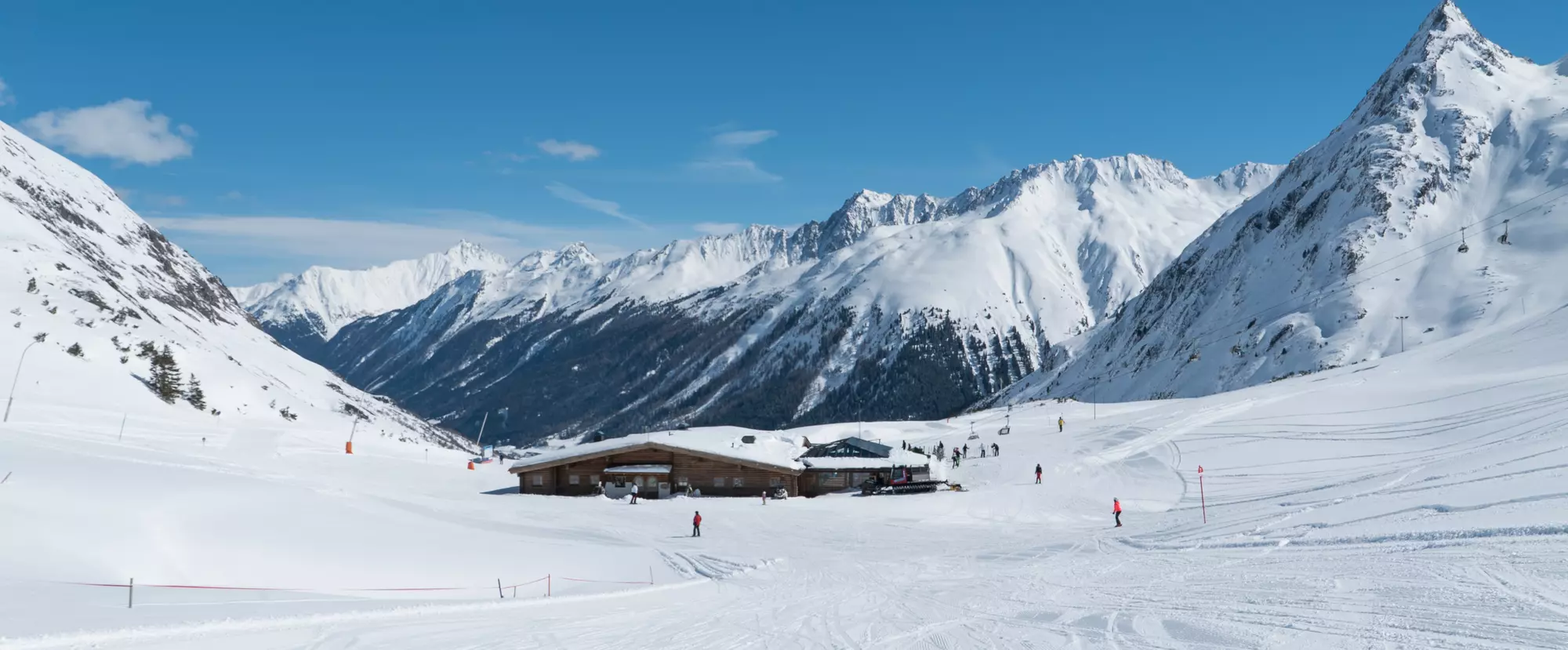 Verschneite Berglandschaft mit Skihütte und Piste bei Sonnenschein
