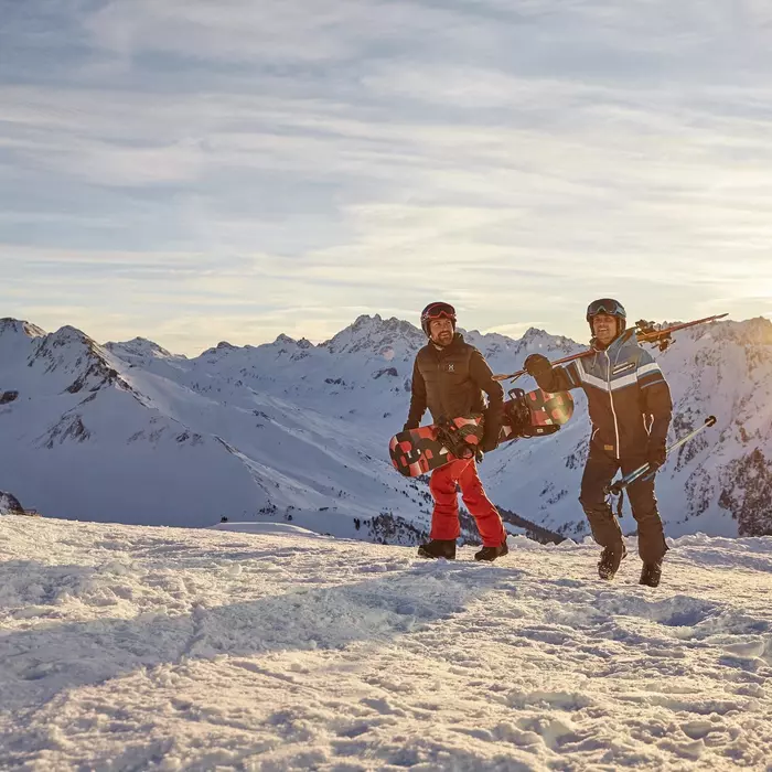 Skifahrer und Snowboarder auf dem Weg zur Piste im Schnee in den Bergen