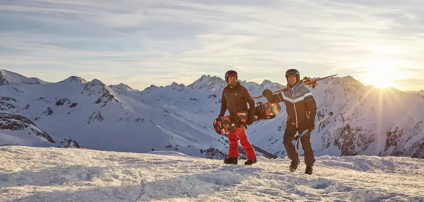 Skifahrer und Snowboarder auf dem Weg zur Piste im Schnee in den Bergen