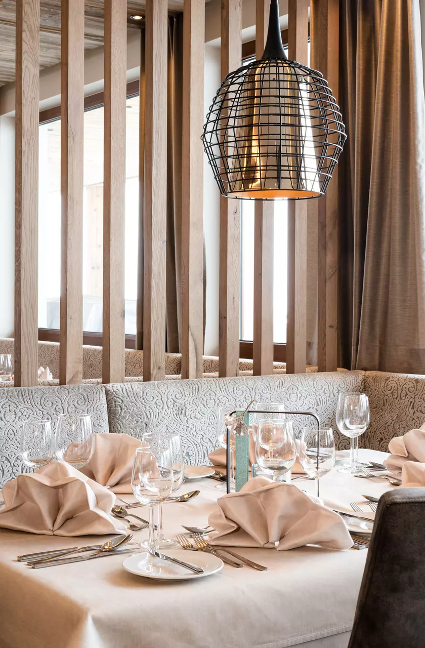 Festlich dekorierter Tisch mit Servietten und Weingläsern unter einer modernen Deckenlampe