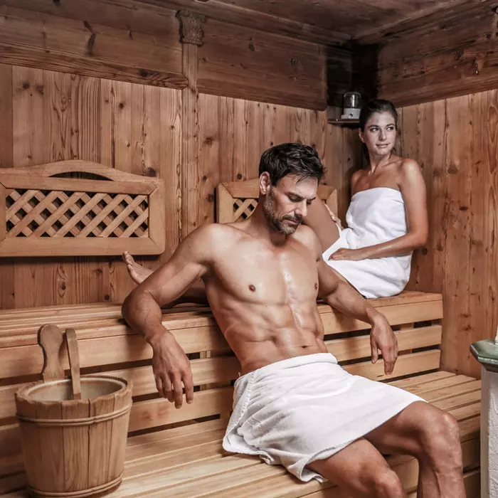 Pärchen mit Badetüchern sitzt schwitzend in der Sauna