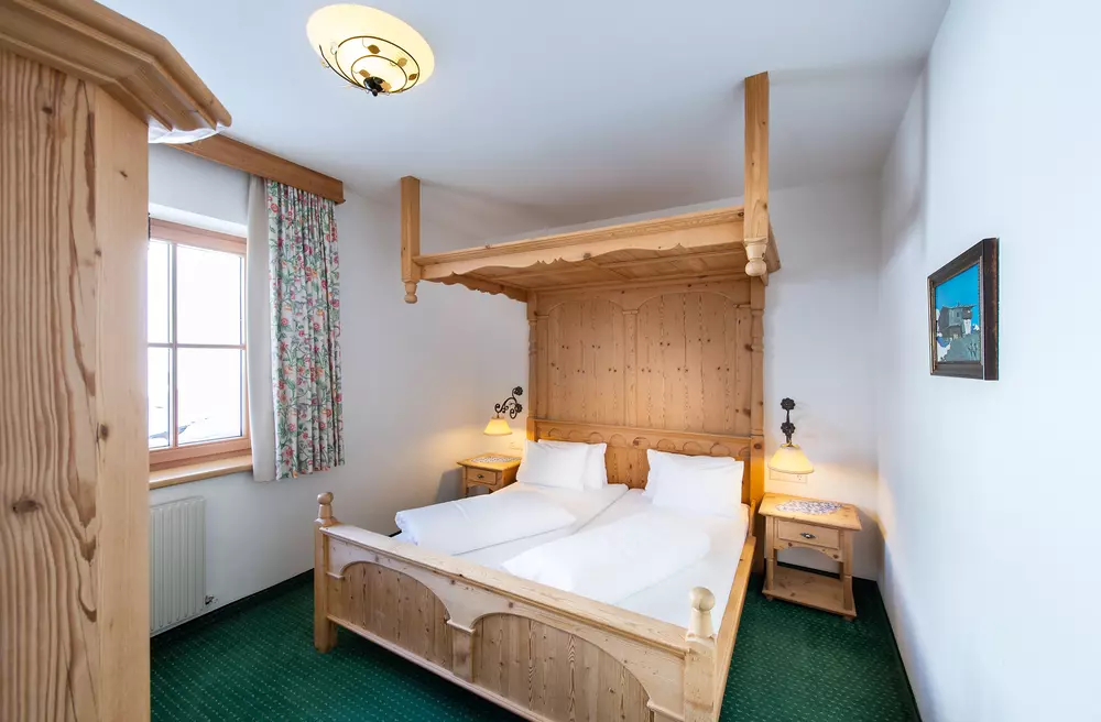 Himmelbett aus Holz in einem Hotelzimmer mit schlichter Einrichtung