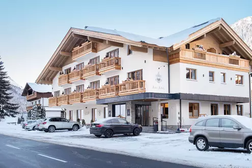 Fassade und Parkplatz des Hotel Glöckner im Winter bei Neuschnee und Sonnenschein